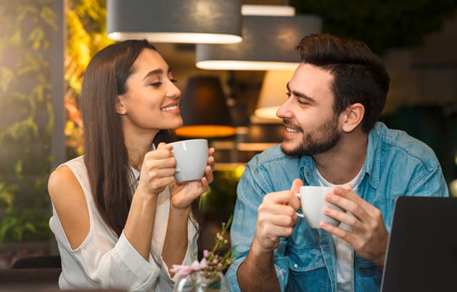Vera-Birkenbihl-Online-Sprachkurs-sich-naeher-kennenlernen-Klarsicht-Verlag Zwei Personen sitzen eng zusammen im Café und sehen sich sympathisch laechelnd an.