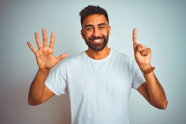 Vera-Birkenbihl-Online-Sprachkurs-Zahlen-lernen-Klarsicht-Verlag Ein Mann sieht lustig in die Kamera und zeigt mit seinen erhobenen Haenden einmal fuenf Finger und einmal einen Finger.