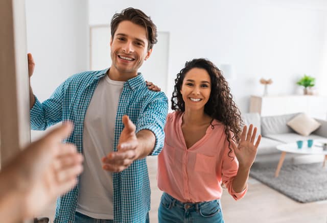 Vera-Birkenbihl-Online-Sprachkurs-andere-kennenlernen-Klarsicht-Verlag Zwei sympathische Personen oeffnen ihre Wohnungstuer und begruessen herzlich einen Besucher.